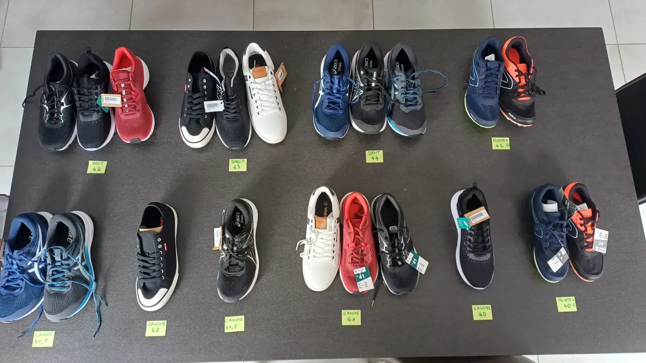 Assortiment de baskets et chaussures de sport neuves, majoritairement noires, bleues et rouges,