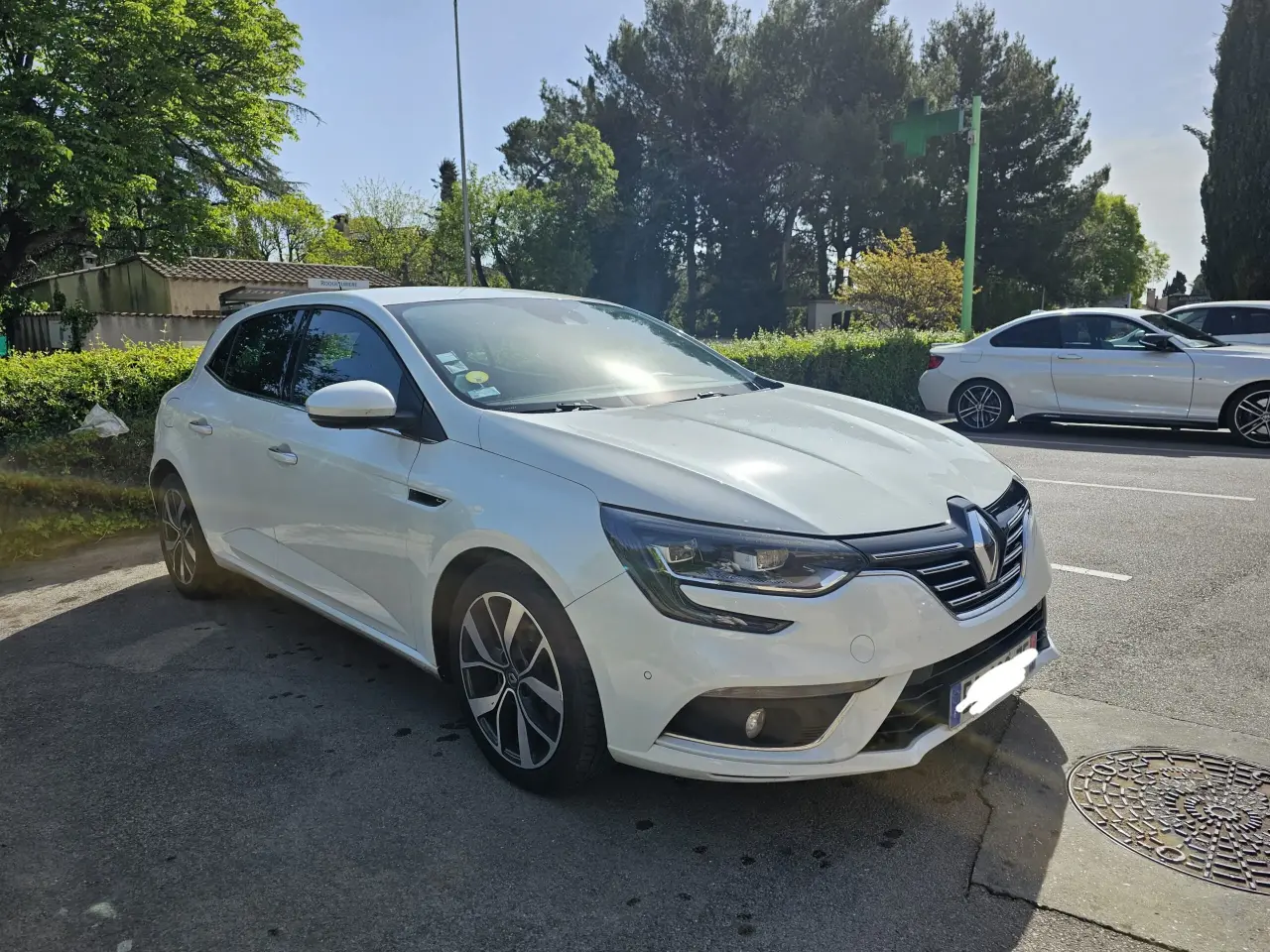 Berline compacte Renault Mégane 4 blanche, carrosserie métal et vitres verre, en bon état général avec des jantes alliage bicolores