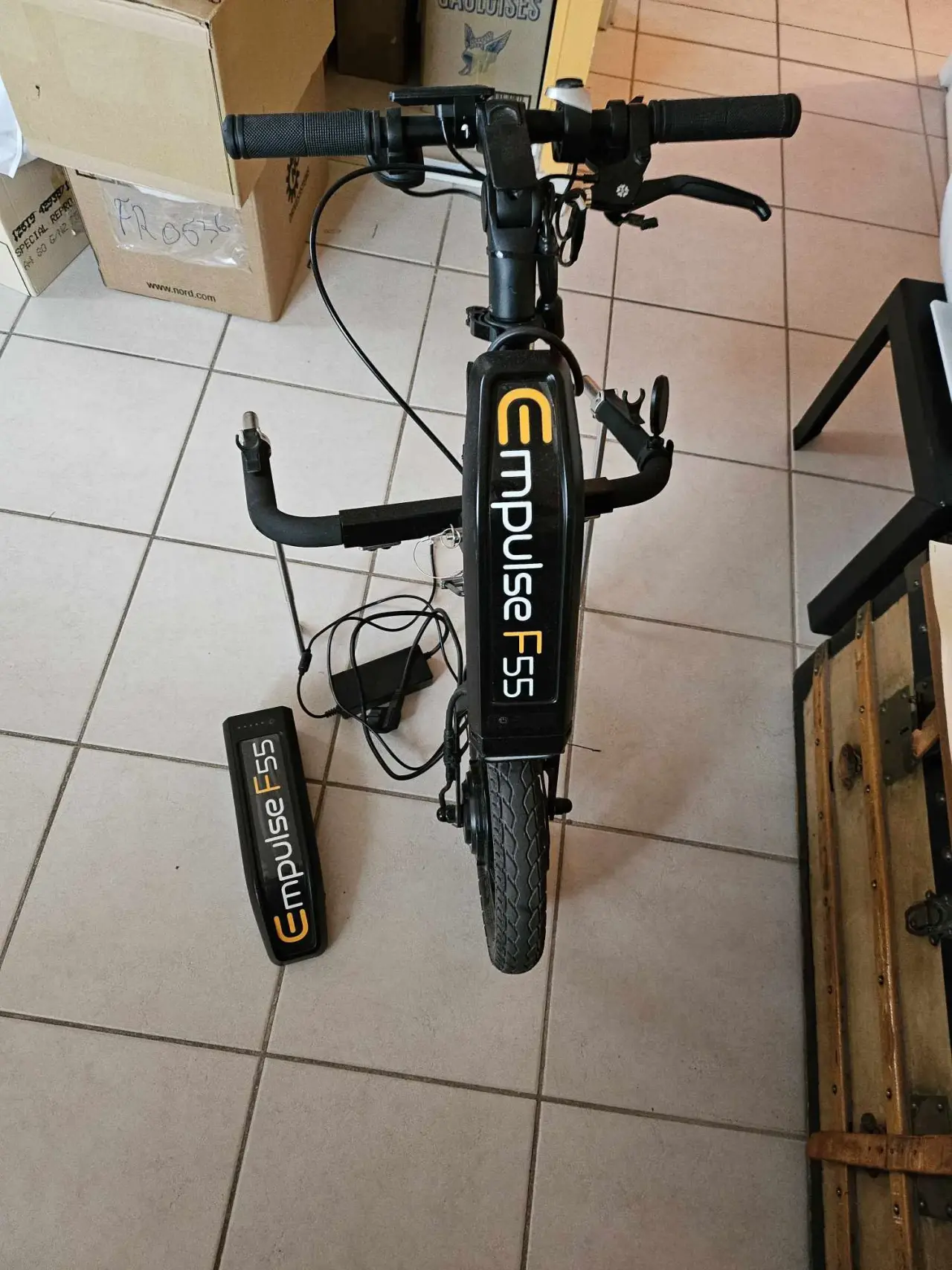 Trottinette électrique Empulse F55 noire, en métal, plastique et caoutchouc, en bon état, avec sa batterie amovible posée à côté