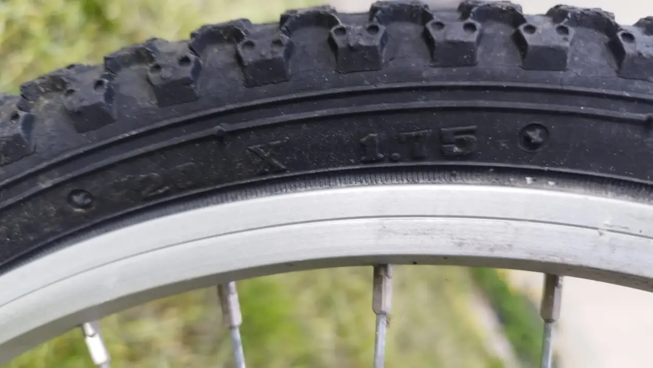 Pneu de VTT noir en caoutchouc, de taille 26 X 1.75 clairement visible sur le flanc, monté sur