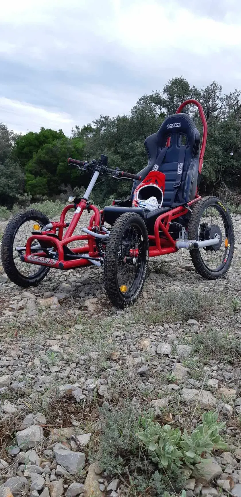 Quadrix tout-terrain électrique rouge vif, châssis métallique robuste, siège Sparco noir, pneus crantés, en excellent état