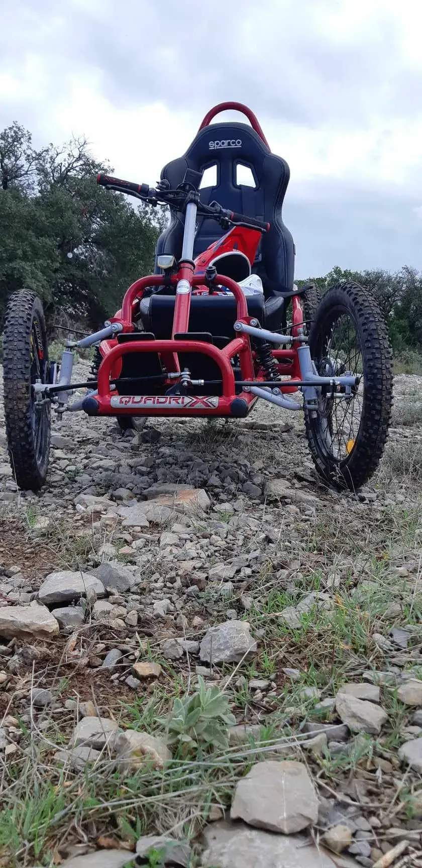 Quadricycle handbike tout-terrain rouge vif, châssis métallique et siège baquet Sparco noir