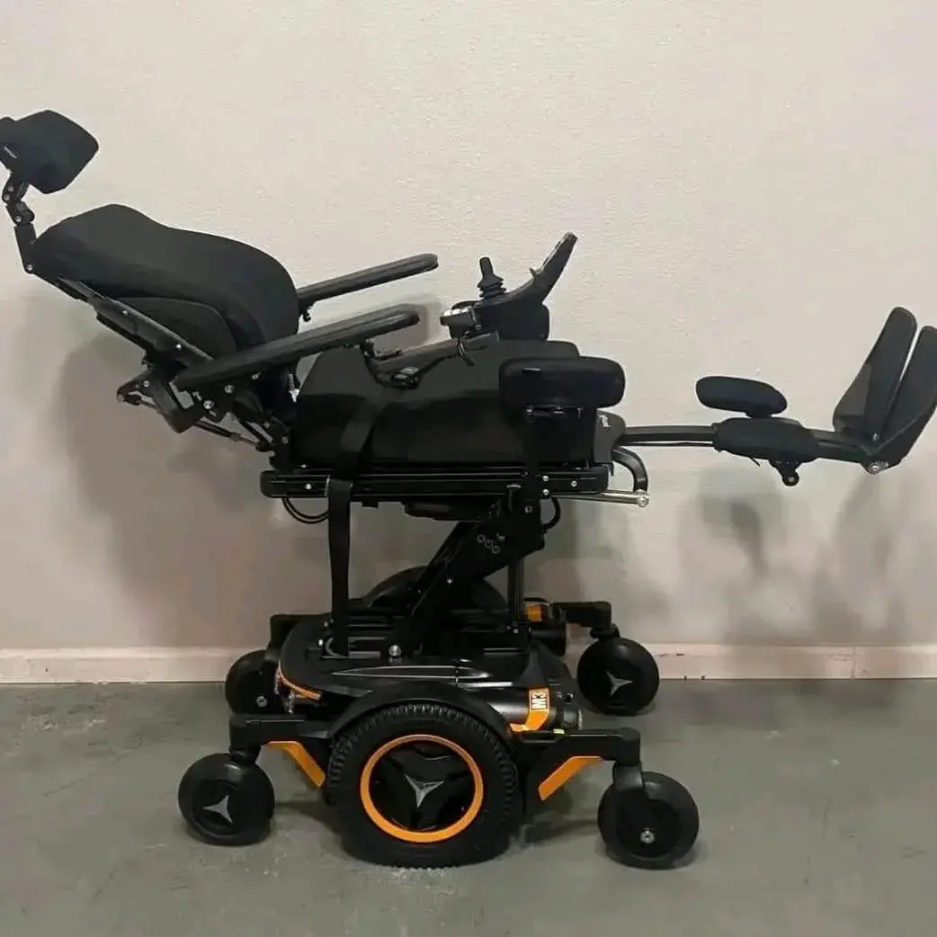 Fauteuil roulant électrique noir et orange en excellent état, avec châssis métallique, siège ergonomique en