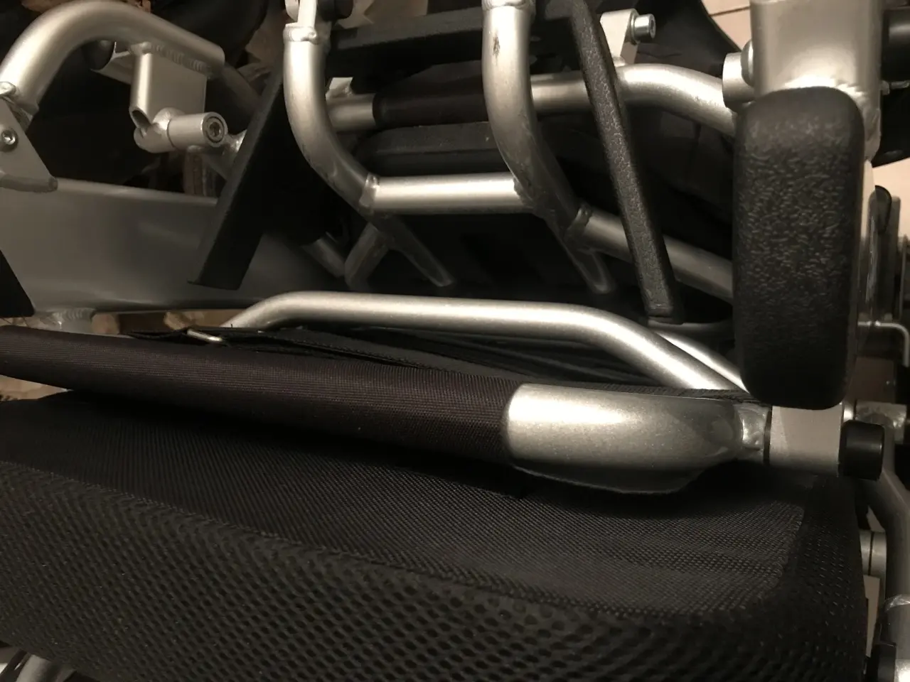 Fauteuil roulant manuel avec cadre robuste en aluminium brossé argenté et sellerie en textile noir maillé