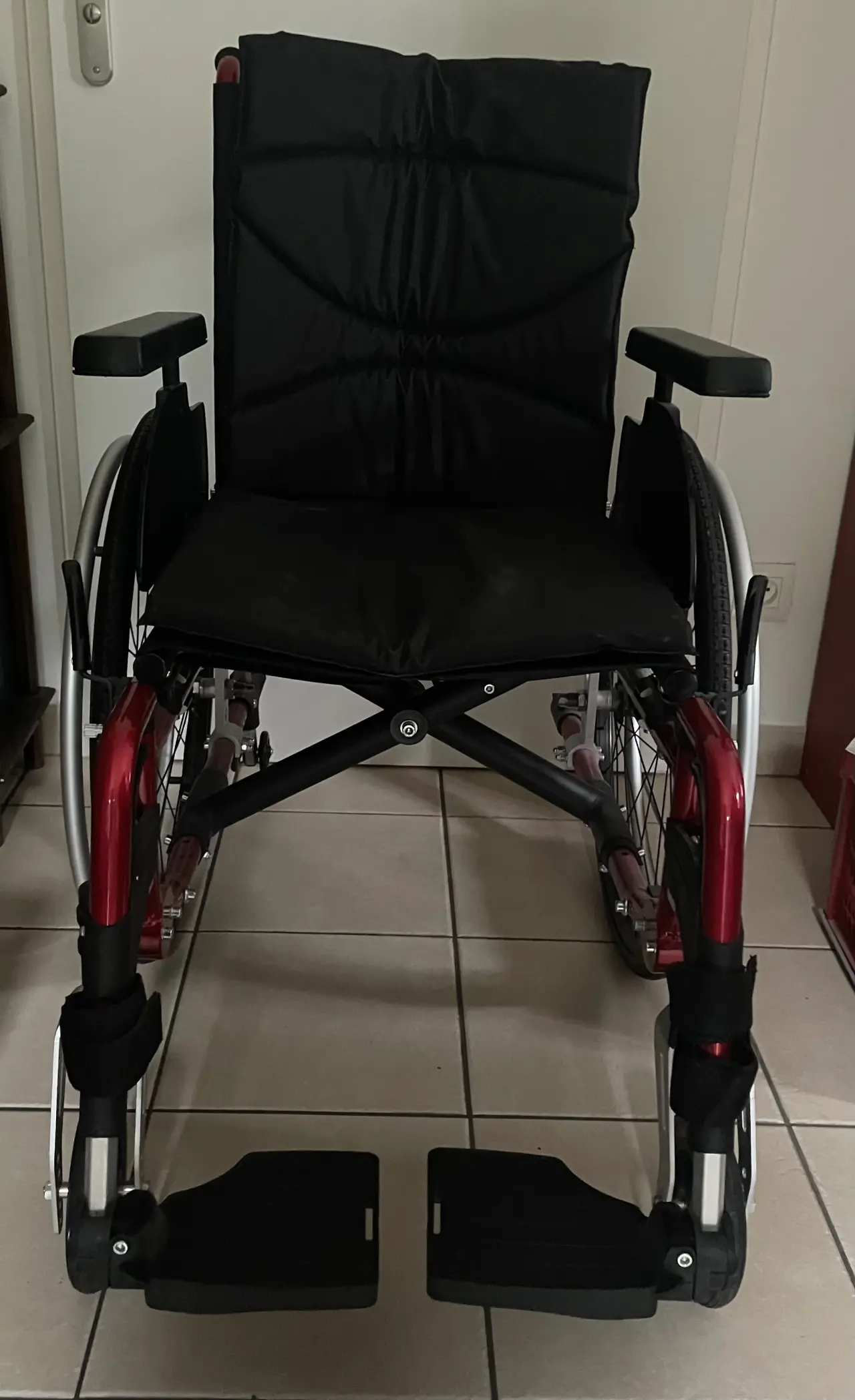 Fauteuil roulant manuel noir et rouge en métal et tissu rembourré, en excellent état, avec un châss
