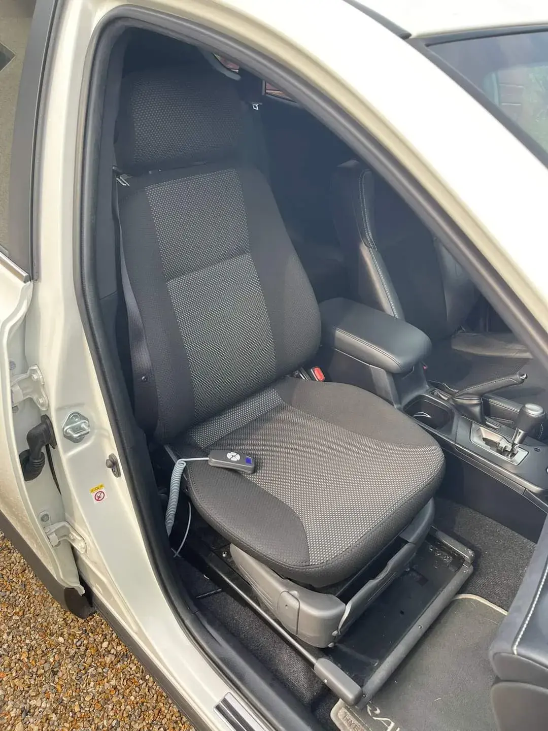 Siège auto pivotant noir en tissu et plastique, avec télécommande filaire intégrée, pour faciliter l'accès au véhicule, en excellent état
