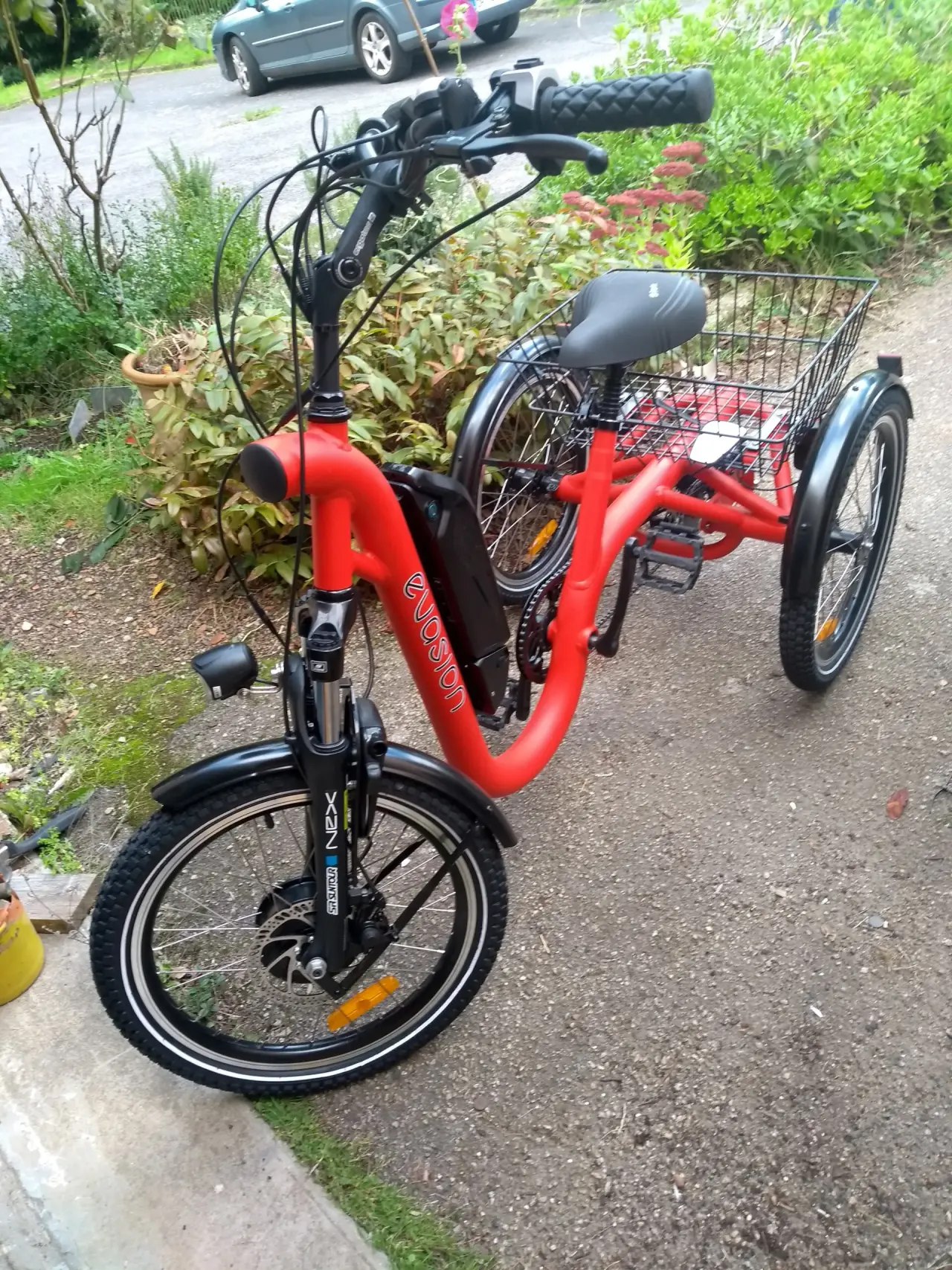 Tricycle électrique rouge vif en métal, en excellent état général, doté d'une batterie noire,