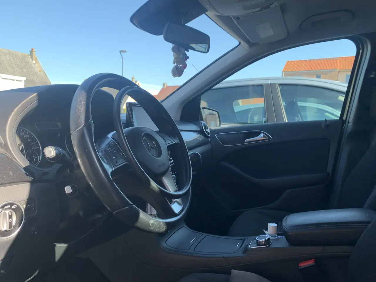 Intérieur de Mercedes-Benz aux tons sombres, mêlant cuir et plastique, montrant un volant
