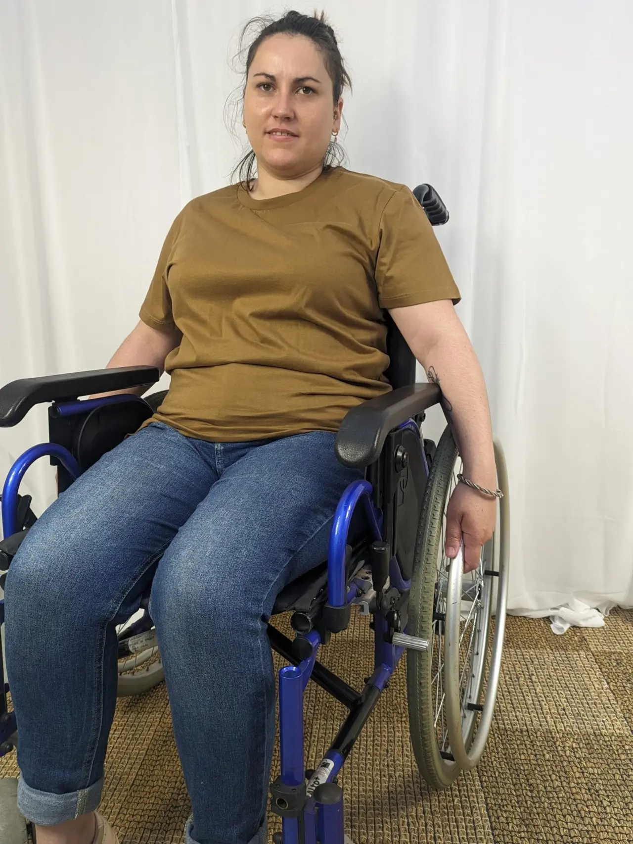 Fauteuil roulant manuel avec un cadre métallique bleu vif, une assise en tissu noir, des roues