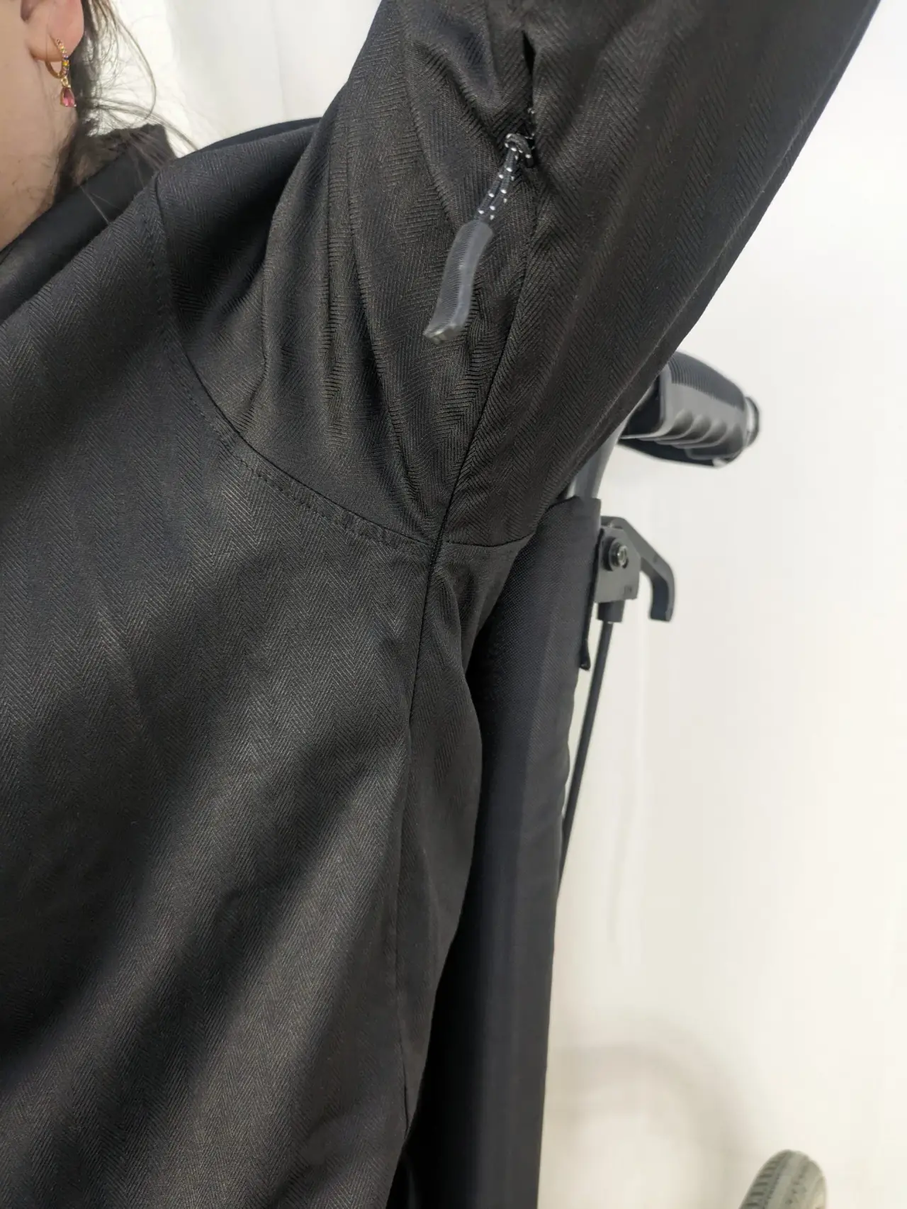 Manche de veste ou manteau technique d'un noir intense, caractérisée par un motif tissé en chevrons prononcé et une texture légèrement